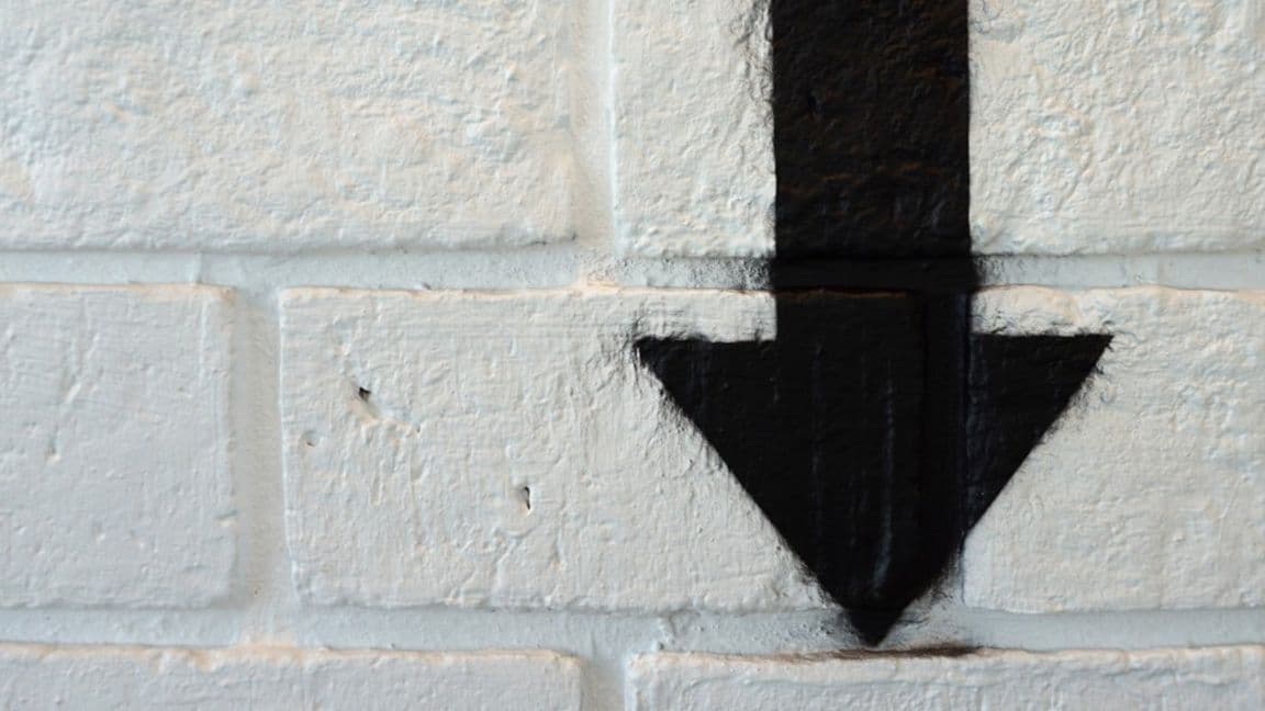 16:9: Down Arrow spray painted on a brick wall (Shutterstock)