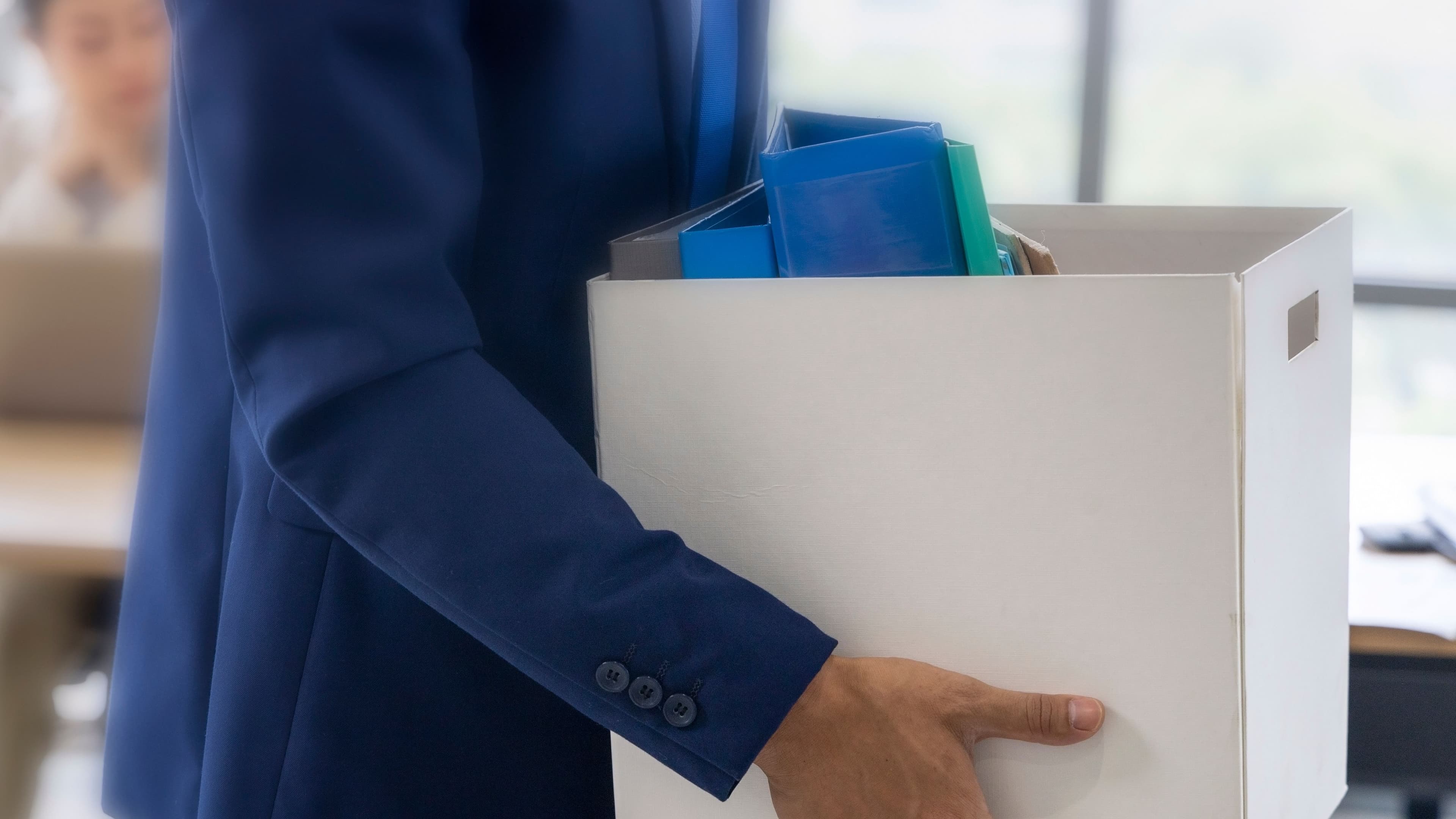 An unemployed with her cardboard box walking out of the work office (Anchalee Phanmaha/Getty Images)